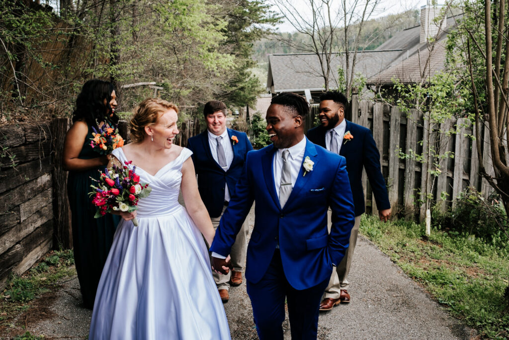 small bridal party with green bridesmaid dresses and navy suits walking