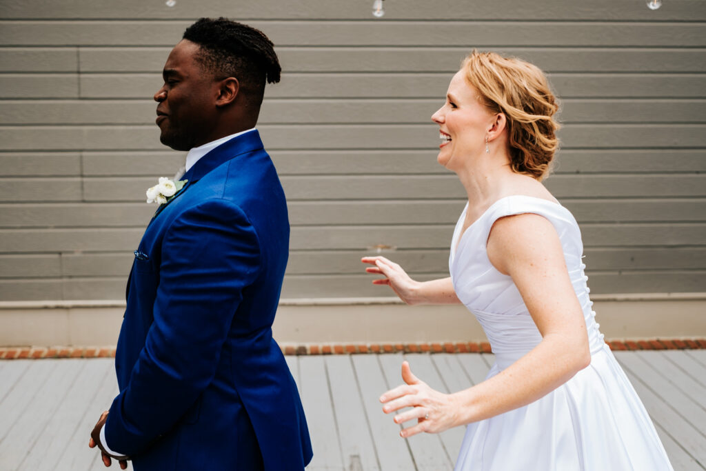 groom with his back to the bride and the bride walking up behind him getting ready to hug him from behind