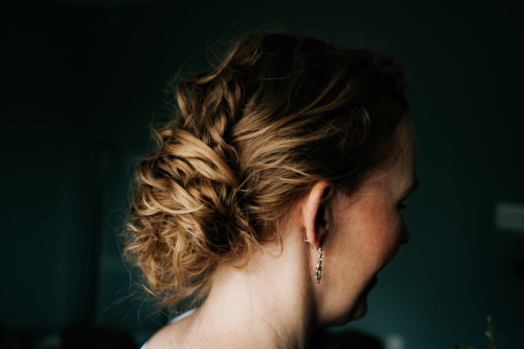 bride with red curly hair with hair in an updo that tucks her hair into a sort of low bun.