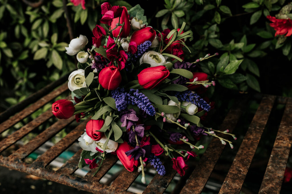 bridal bouquet with pink purple greenery and white flowers on a metal bench