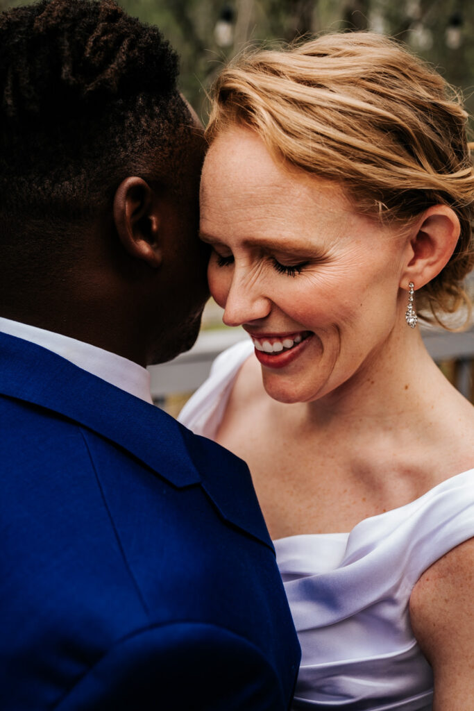 brides face smiling and eyes down cuddled up to her groom