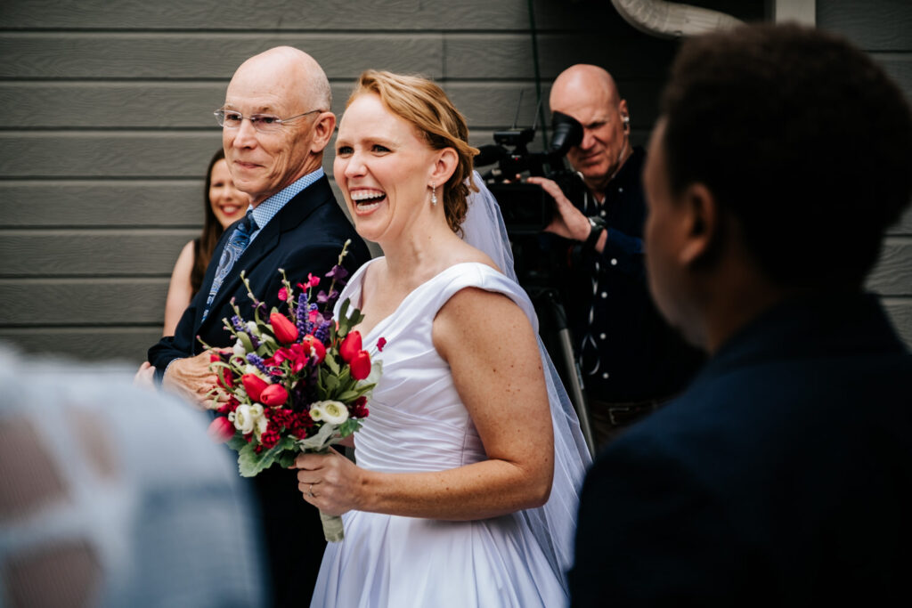 bride laughing while walking down the aisle