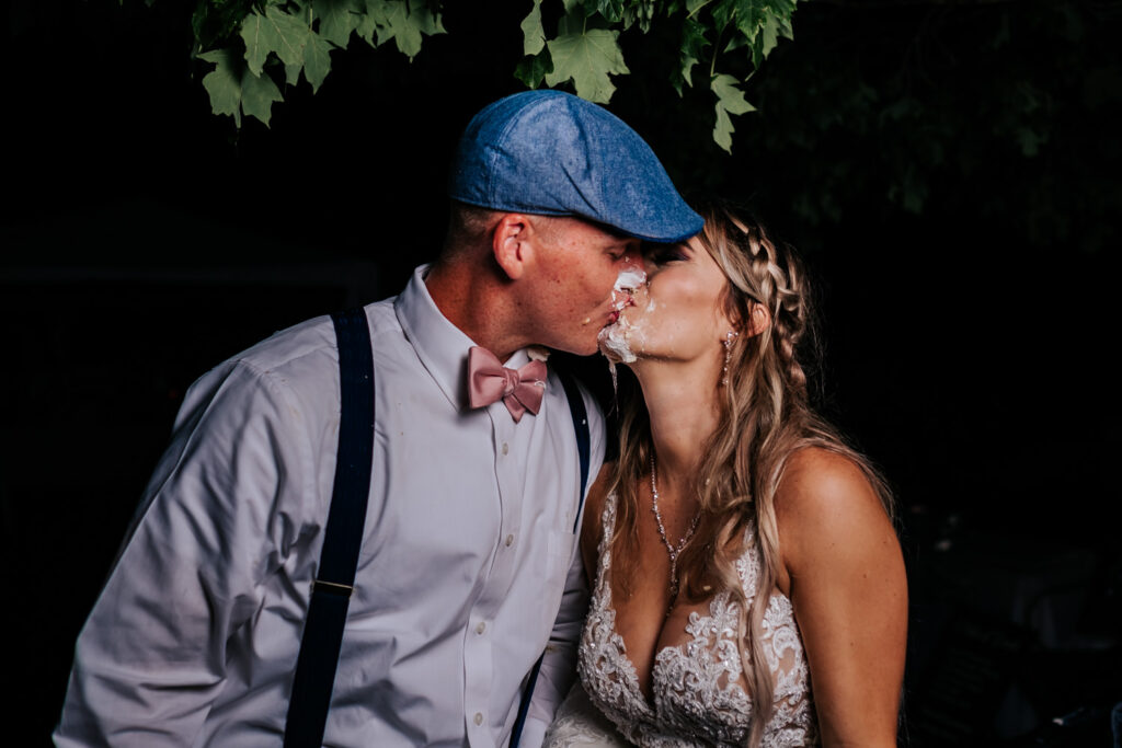 bride and groom kissing with cake all over their faces