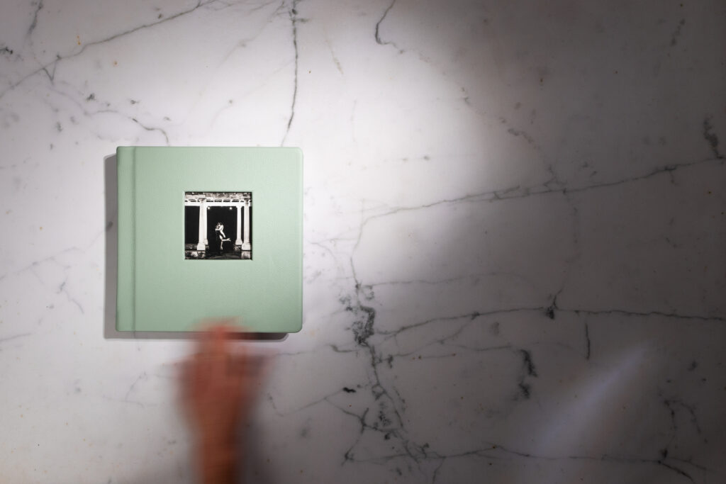 A wedding photo album sitting on a marble table top.